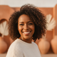 Headshot of a smiling North American woman in her late 30s with diverse features, against a soft background.