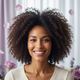 Close-up portrait of a smiling woman with voluminous, styled curls, looking happy and confident.